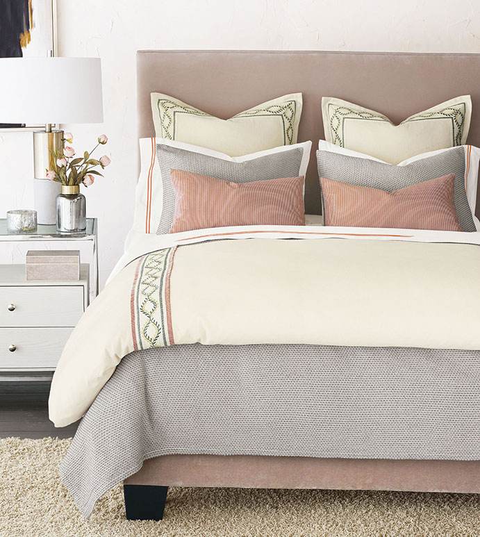 Elegant bedroom with pink decor, featuring a plush pink upholstered headboard, soft blush accent pillows, neutral bedding, and a modern nightstand with stylish accents.