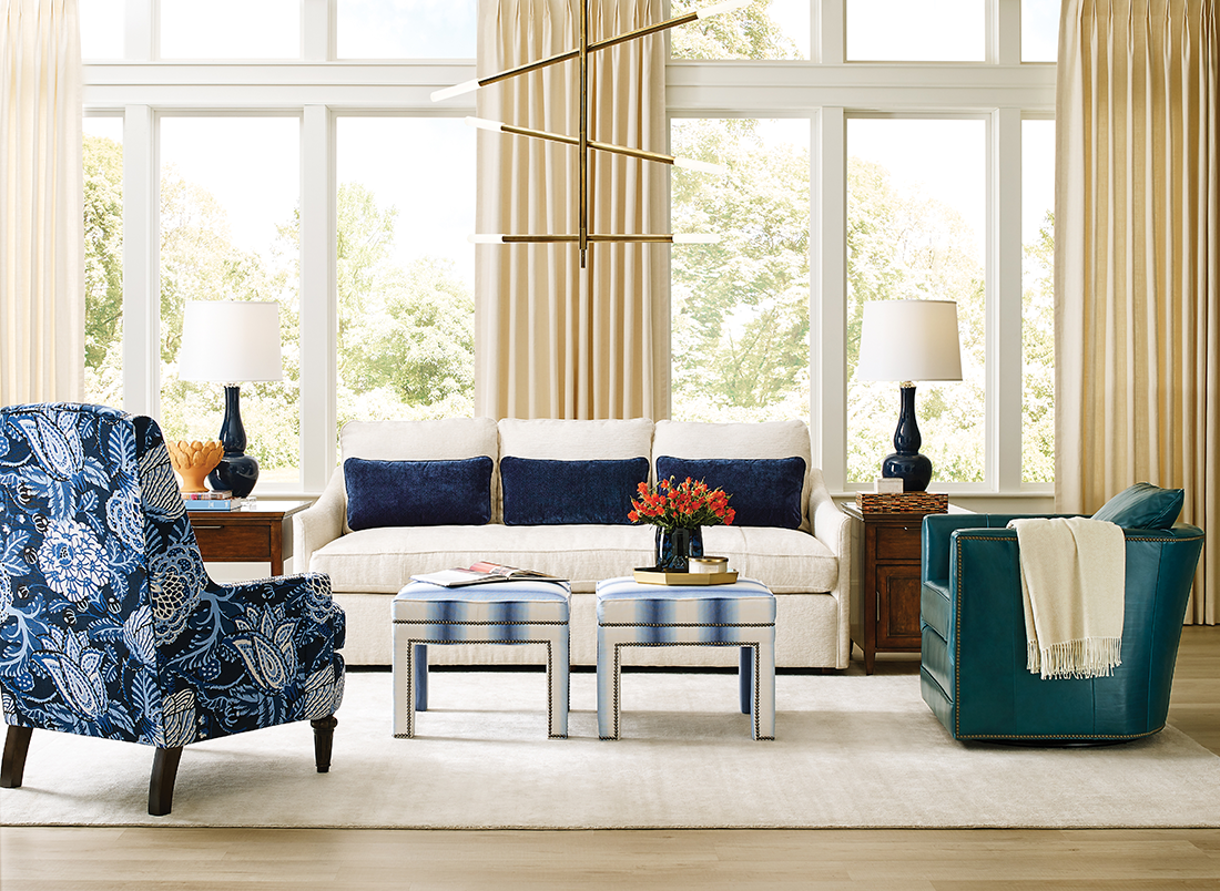 Elegant living room featuring classic furniture with bold accents, including a cream sofa, floral armchair, and rich wood end tables.