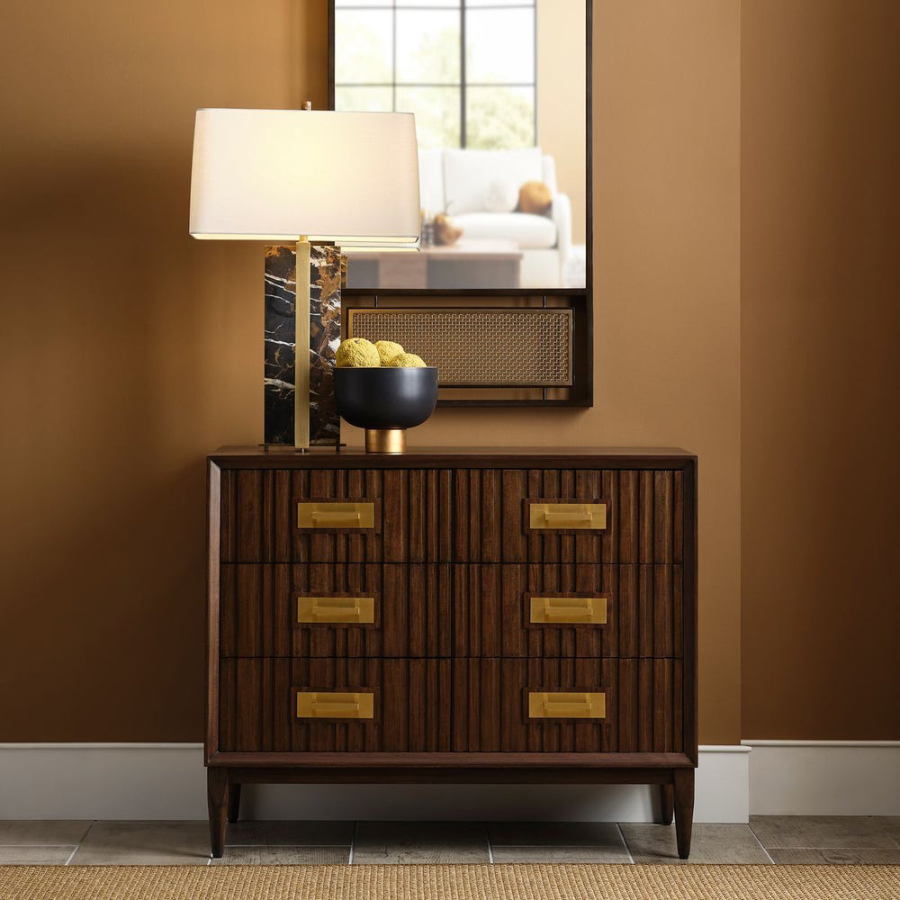 High-end home decor entryway with a dark wood console table, gold-accented drawers, modern marble lamp, and decorative mirror for a luxurious interior touch.