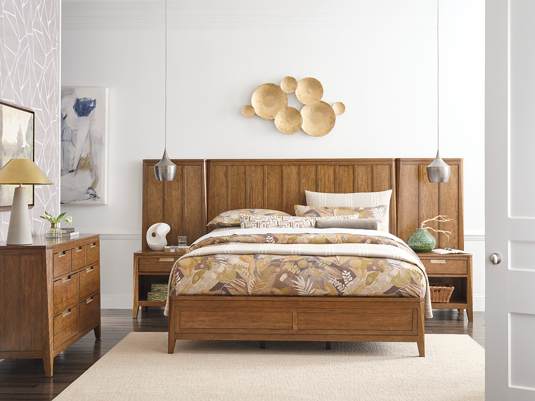 Bedroom featuring warm wood furniture with a solid cherry bed frame, matching nightstands and dresser, layered neutral bedding, and modern decorative accents.